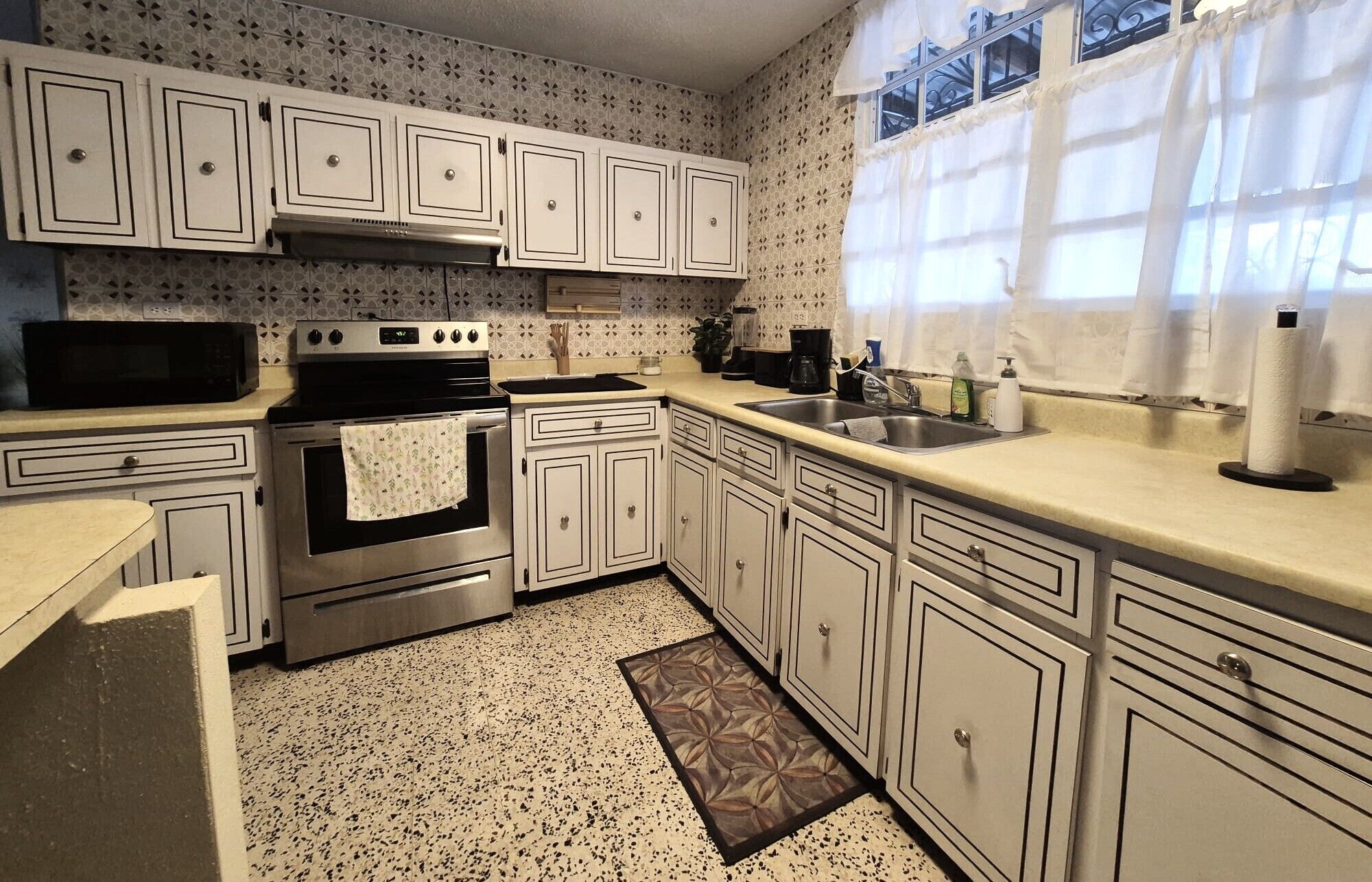 A kitchen with white cabinets, a stainless steel stove, and a sink.