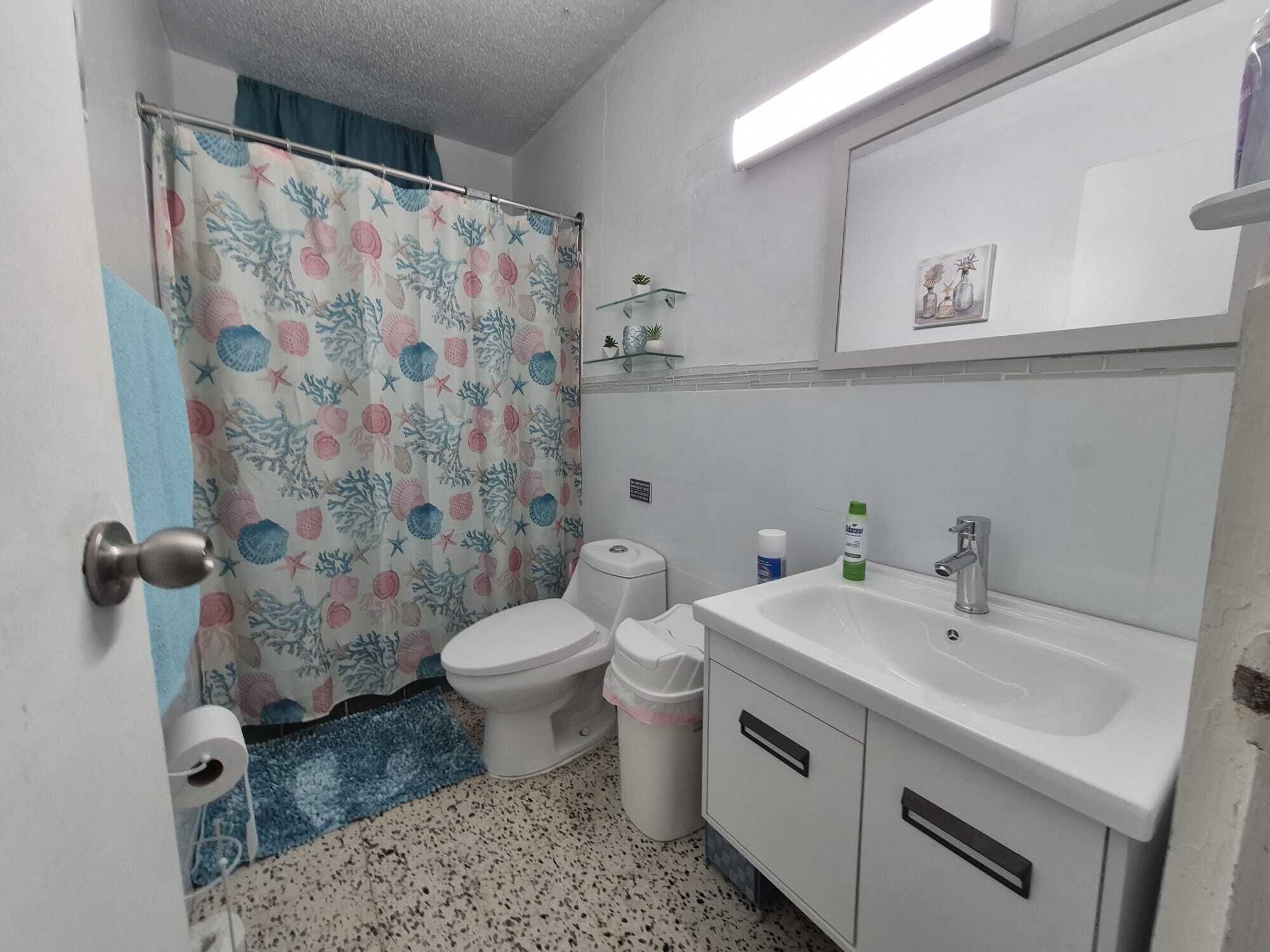 Un baño con inodoro, lavamanos y cortina de ducha.