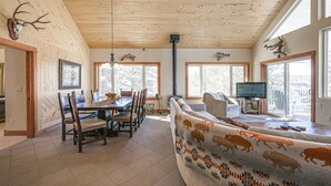 A spacious living room with a large sofa, a dining area with a wooden table and chairs, and a fireplace. - Pagosa Springs Family Retreat w/ Game Room & Views (Pagosa Springs)