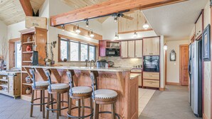 A spacious kitchen with a large island, bar stools, wooden cabinets, and a built-in microwave. - Pagosa Springs Family Retreat w/ Game Room & Views (Pagosa Springs)