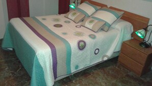 Un lit avec une couvre-lit à motifs, deux oreillers et une table de chevet avec une lampe.