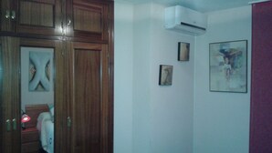Une chambre avec une armoire en bois, un appareil de climatisation et un lit.