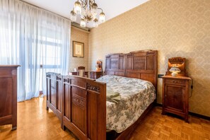 Une chambre à coucher avec un lit en bois, une table de chevet, une commode et un lustre.