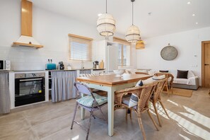 Une cuisine moderne avec un coin repas, des meubles en bois et des chaises en osier.