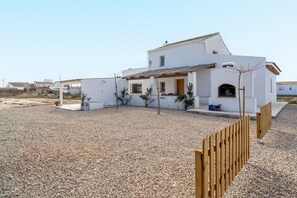 A white building with a gravel driveway and a wooden fence.