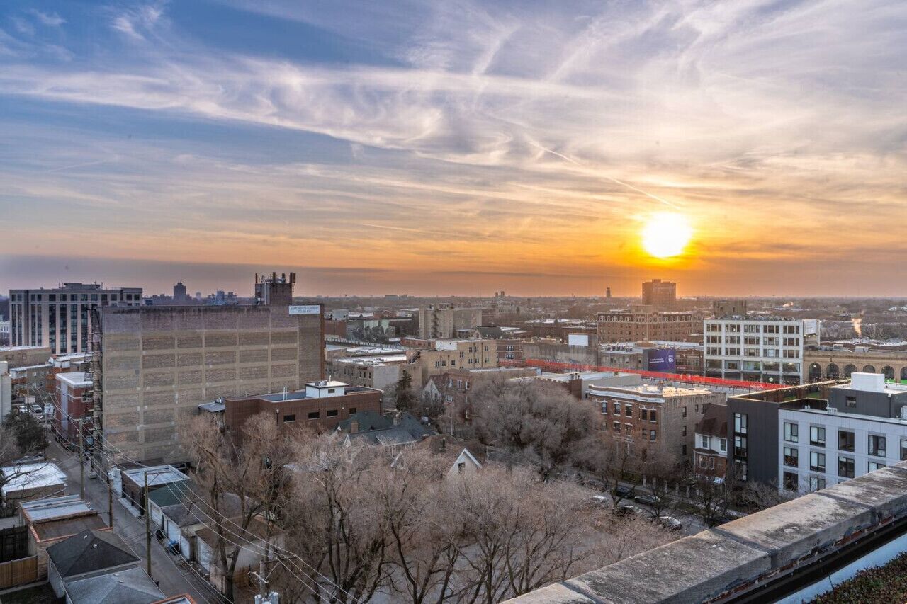 Une vue urbaine avec un coucher de soleil sur les bâtiments et une voie ferrée.