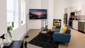 Ein modernes Wohnzimmer mit einer Couch, einem Couchtisch und einem Flachbildfernseher.