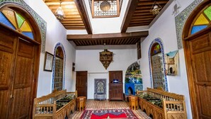 A traditional interior with wooden benches, a patterned rug, and a central hanging light fixture.