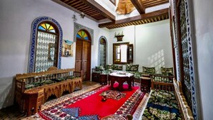 A traditional room with a red carpet, wooden furniture, and decorative arches.