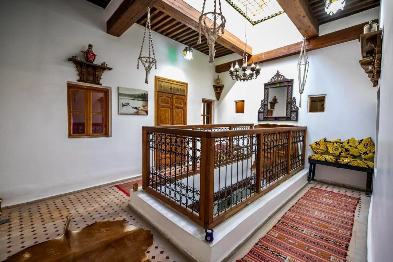 Een traditioneel interieur met een houten balkon, een kamerbreed tapijt met dessin en een bank met kussens.