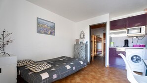 Une pièce de taille modeste comprenant un lit, un petit bureau, un lave-linge et un four à micro-ondes.