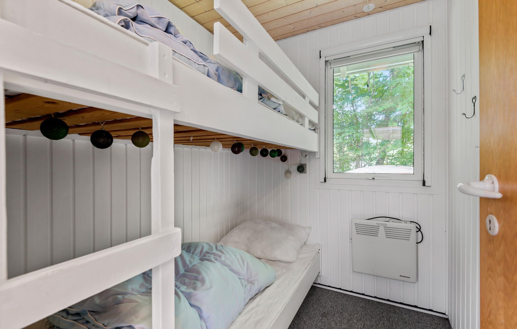 A bunk bed room with a window, a heater, and a door.