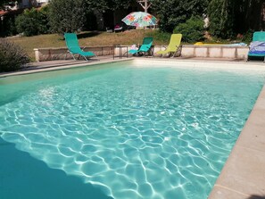 Una piscina con agua cristalina y sillones de descanso alrededor.