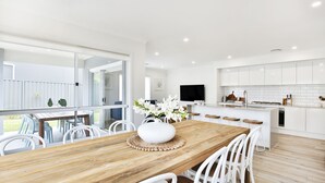 A modern kitchen with white cabinets, a wooden island, and a TV mounted above the counter. - The Coast Beach - Pet Friendly - 2 Mins Walk to Bay (Callala Bay)