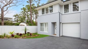 A modern two-story house with a grey exterior, white shutters, and a concrete driveway.