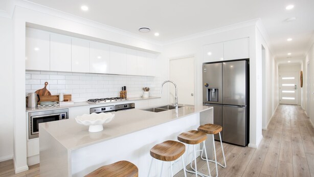 A modern kitchen with white cabinetry, a stainless steel refrigerator, a built-in oven, and a large island with bar stools. - The Coast Beach - Pet Friendly - 2 Mins Walk to Bay (Callala Bay)