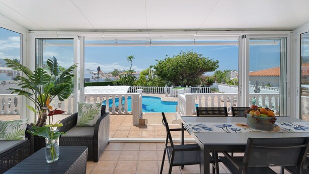 Ein Balkon mit Pool, weißen Möbeln und Blick auf die Stadt.