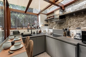 A modern kitchen with a stone wall, a large window, and a dining area with a table set for two.