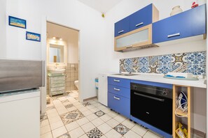 Une cuisine compacte avec des meubles bleus, un lave-vaisselle et un dosseret carrelé.