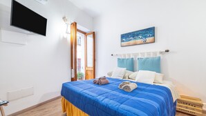 Une chambre à coucher avec un lit, une télévision, un tableau et une boîte en bois étiquetée « RANGEMENT ».
