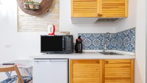 Une cuisine compacte équipée d’un four à micro-ondes, d’une machine à café et d’un évier.