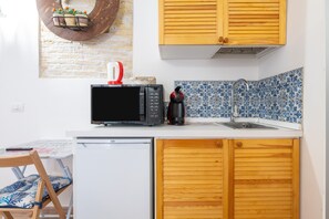 A compact kitchen with a microwave, coffee maker, and a sink.