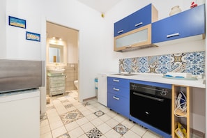 Cozinha com armários azuis, máquina de lavar louça e painel de azulejos.