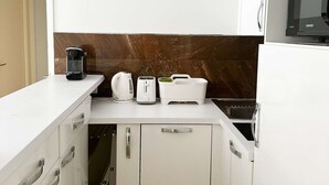 A small kitchenette with white cabinets, a microwave, a toaster, and a coffee maker.