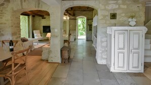 A rustic interior with exposed stone walls, wooden furniture, and a central archway leading to a bright outdoor area. - Charming Cottage in Fargues (Prayssac/Montcuq) — Private Pool & Spa, Vineyard View (BAGAT EN QUERCY)