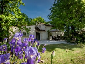 Ein Haus mit Garten, Terrasse und Tisch mit Stühlen.