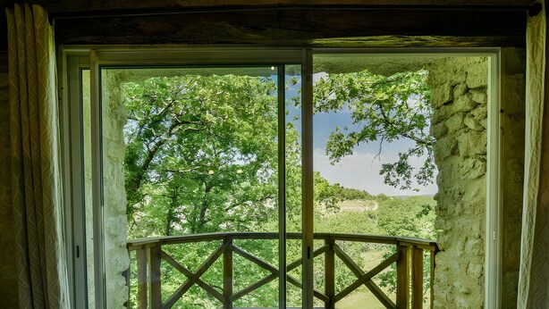 A wooden deck with a railing, a stone wall, and a view of trees and hills. - Charming Cottage in Fargues (Prayssac/Montcuq) — Private Pool & Spa, Vineyard View (BAGAT EN QUERCY)