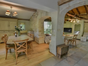 Una cocina rústica con muebles de madera, paredes de piedra y un comedor con una mesa grande y sillas.