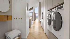 Une buanderie moderne équipée d’un lave-linge, d’un sèche-linge et d’un petit banc sur lequel est posée une serviette.
