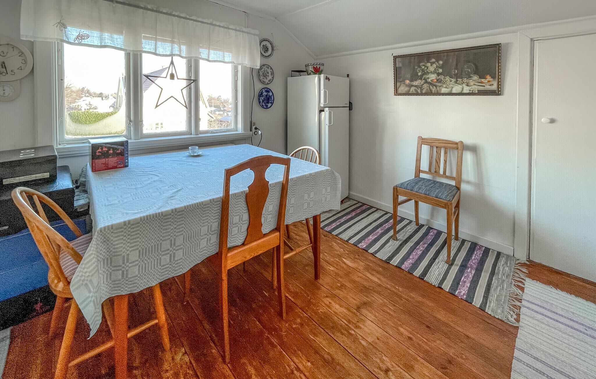 Un coin repas avec une table dressée pour deux personnes, un réfrigérateur et une chaise.