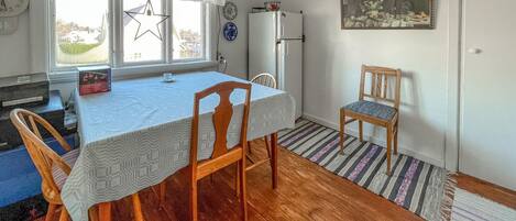 Un coin repas avec une table dressée pour deux personnes, un réfrigérateur et une chaise.