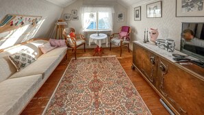 A cozy living room with a sofa, chairs, a coffee table, a patterned rug, and a cabinet with decorative items.
