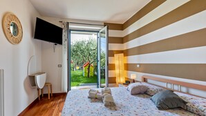 A bedroom with a bed, a TV, a desk, and a view of the outside. - Bright  apartment 'Bluemoon' with Pool, Wi-Fi and Air Conditioning (LAZISE)