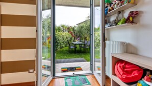 A room with a sliding glass door leading to a patio with a table and chairs, a radiator, and shelves with stuffed toys. - Bright  apartment 'Bluemoon' with Pool, Wi-Fi and Air Conditioning (LAZISE)