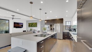 A modern kitchen with a large island, stainless steel appliances, and pendant lighting. - The Gem of Mission Hills: Luxury 5BR Home with Luxe Amenities and views` (San Diego)