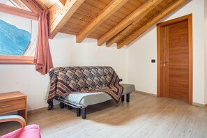 Une chambre à coucher avec un lit, une porte en bois, une fenêtre donnant sur les montagnes et un plafond en bois.