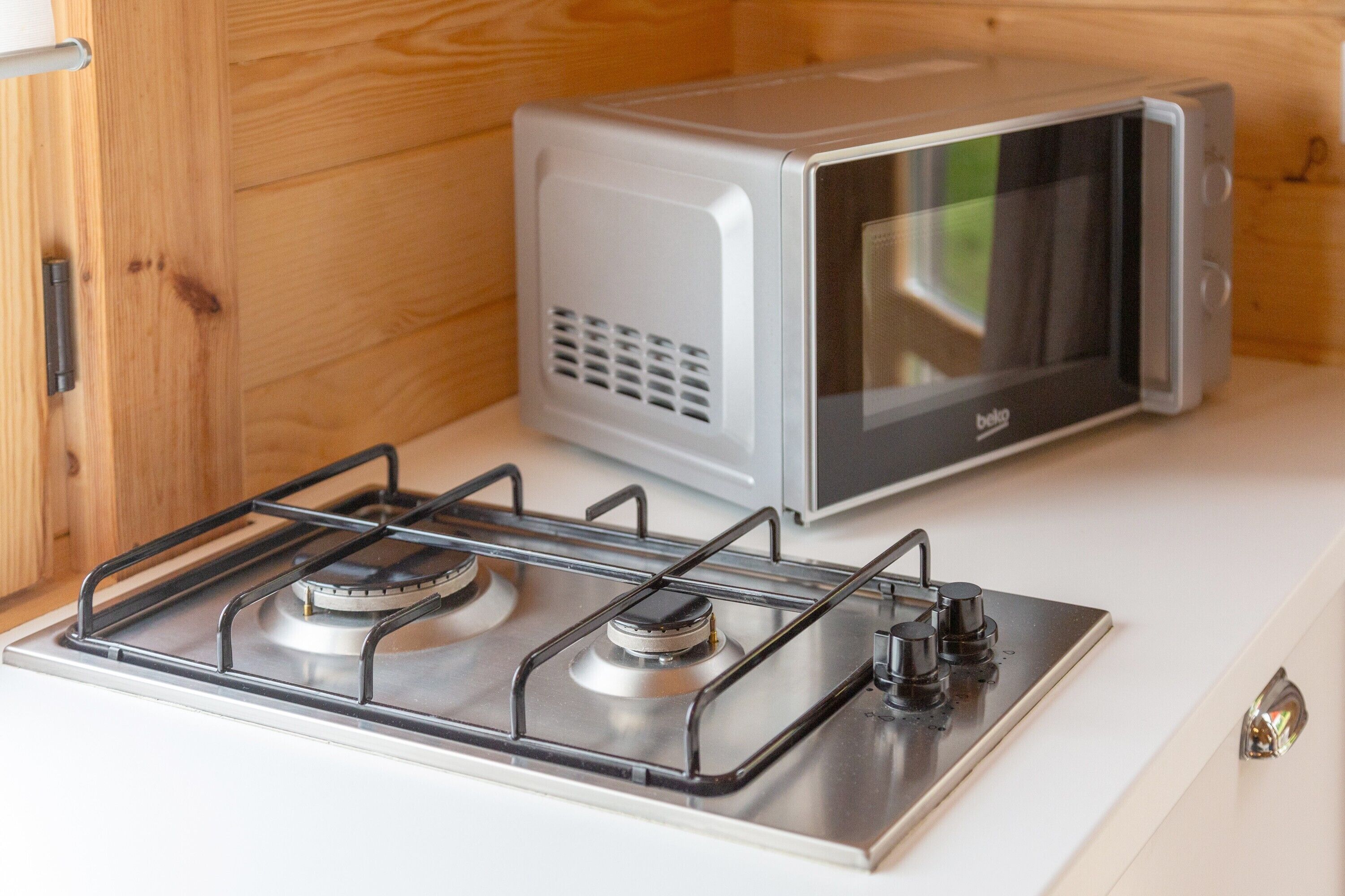 A kitchenette with a gas stove, a microwave, and wooden cabinetry.