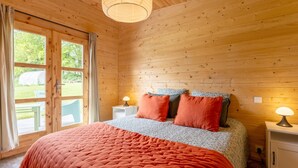 Ein Zimmer mit Holzwänden, einem Bett, zwei Nachttischen und einem Fenster.