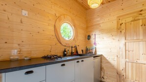 Ein Holzhütten-Interieur mit Küchenbereich, einem Rundfenster und einer Tür.