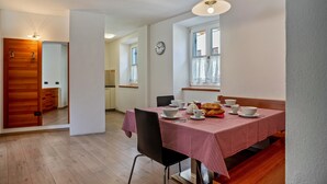 A dining area with a red and white checkered tablecloth, a clock on the wall, and a window with curtains. - Apartment 'Casa Batistei Ribes' with Lake View, Balcony and Wi-Fi (Molveno)
