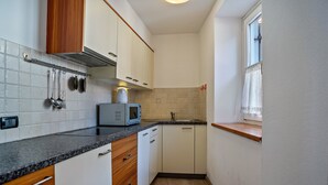 A compact kitchen with white cabinets, a granite countertop, a microwave, and a window with a curtain. - Apartment 'Casa Batistei Ribes' with Lake View, Balcony and Wi-Fi (Molveno)
