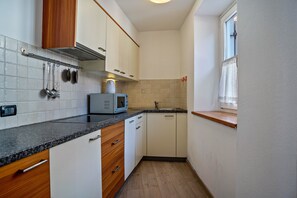 A compact kitchen with white cabinets, a granite countertop, a microwave, and a window with a curtain. - Apartment 'Casa Batistei Ribes' with Lake View, Balcony and Wi-Fi (Molveno)