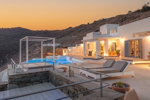 A modern villa with a pool, outdoor seating, and a view of the surrounding hills. - Villa 'Blueros Luxury' with Sea View, Wi-Fi and Air Conditioning (Syros)