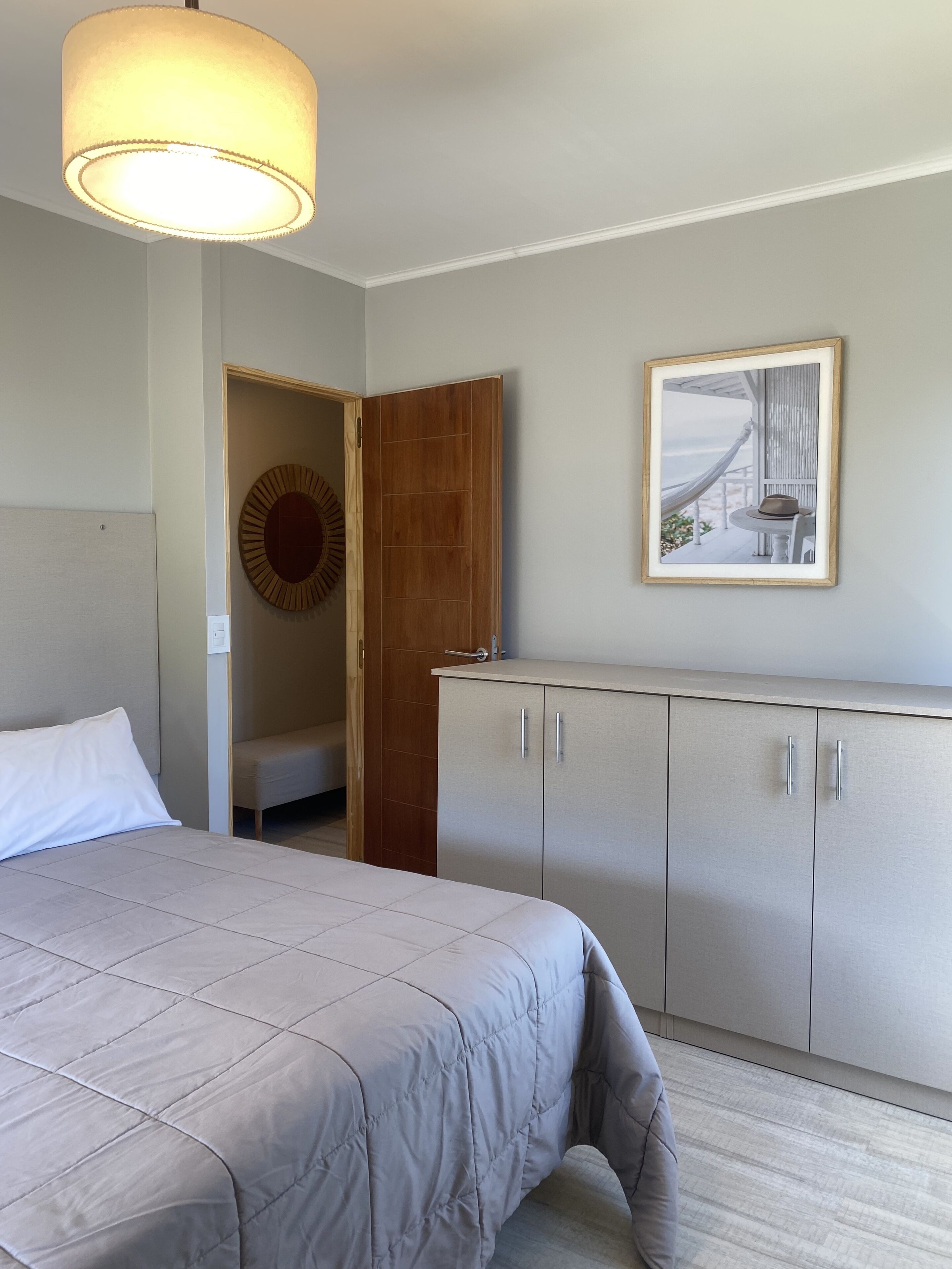 A bedroom with a bed, a wardrobe, a door, and a framed picture on the wall.