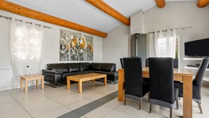 Un salon moderne avec un canapé en cuir noir, une table basse en bois et des chaises de salle à manger.