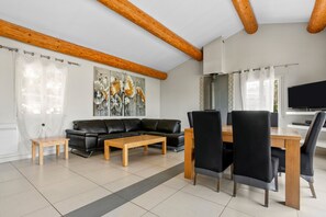 Una sala de estar moderna con un sofá de cuero negro, una mesa de centro de madera y sillas de comedor.
